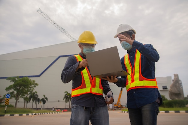 Deux ingénieurs travaillant la technologie informatique sur la construction du site, deux ingénieurs portent un masque pour protéger covid19