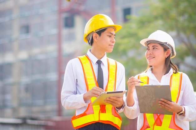 Deux ingénieurs utilisent une tablette et parlent sur le chantier