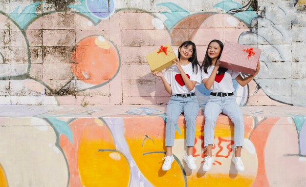 Deux jeune fille heureuse avec boîte présente sur fond coloré. Fille asiatique.