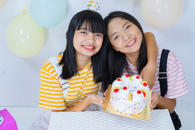 Deux jeune fille heureuse avec un gâteau à la fête.