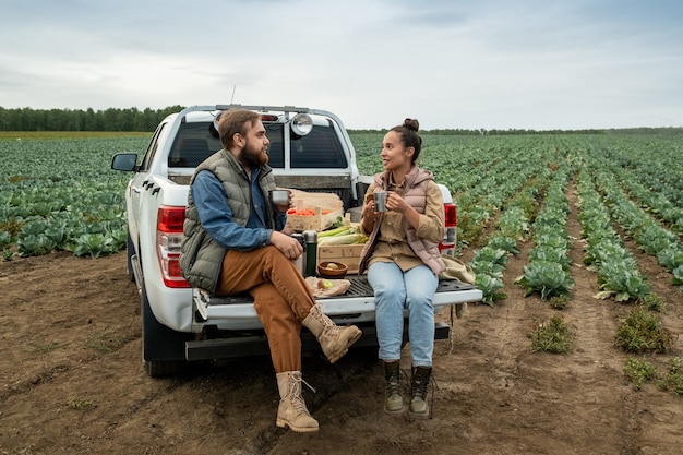 Deux jeunes agriculteurs prenant le thé à la pause après avoir travaillé au champ de chou