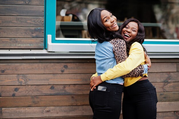 Deux jeunes amies afro-américaines du collège s'embrassent.