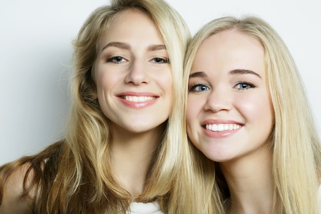 Deux jeunes amies se tenant ensemble et s'amusant. En regardant la caméra.