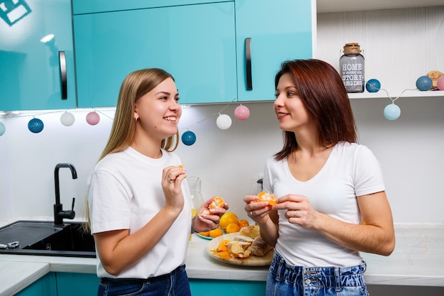 Deux jeunes amies se tiennent dans la cuisine avec des femmes au foyer fraîchement cuites au four partagent des recettes de cuisson