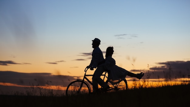 Deux jeunes amoureux d'autres au coucher du soleil un couple sur un vélo