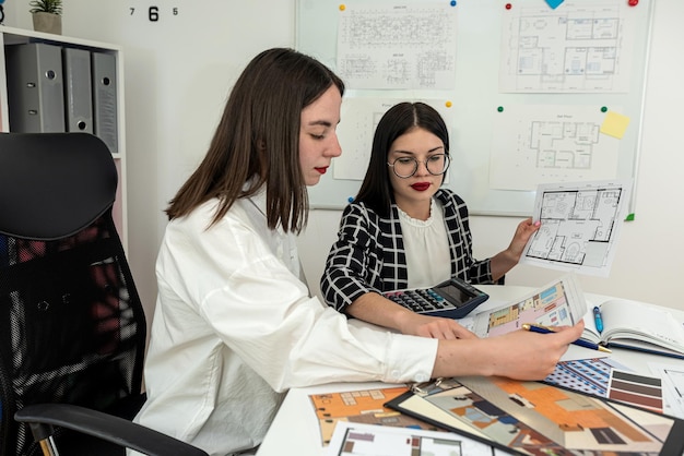 Deux jeunes architectes de race blanche travaillent ensemble pour modifier le projet de plan de maison au bureau