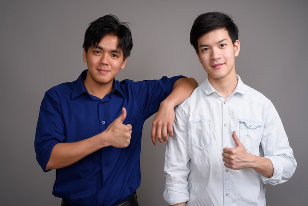 deux jeunes beaux hommes asiatiques sur gris