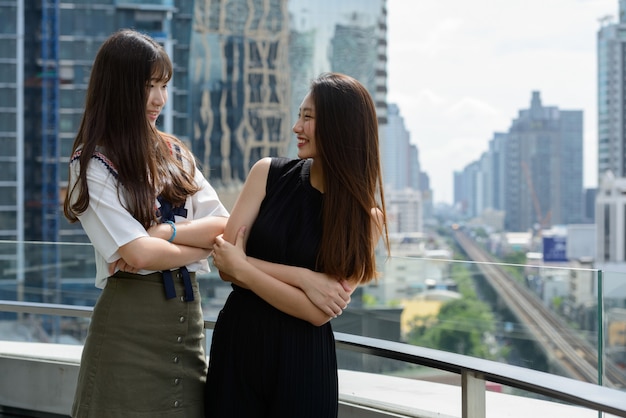 Deux jeunes belles adolescentes asiatiques heureux souriant à l'autre contre vue sur la ville