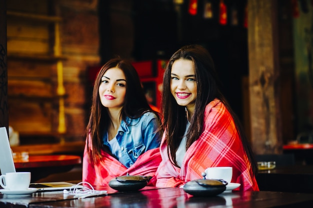 Deux jeunes et belles filles assises à la table et cherchant quelque chose sur Internet