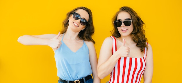 Deux jeunes belles filles hipster souriantes blondes dans des vêtements d'été à la mode