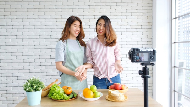 Deux jeunes blogueuses alimentaires asiatiques discutant lors de l'enregistrement d'une vidéo avec un moment de bonheur