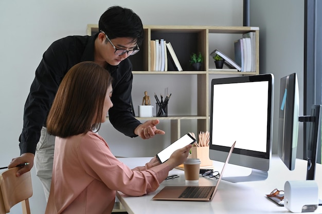 Deux jeunes collègues de travail travaillant avec une tablette numérique au bureau