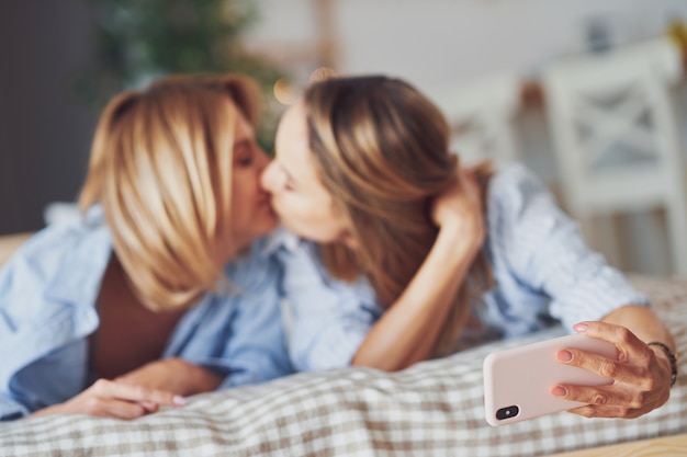 Deux jeunes copines sur le lit prenant selfie. photo de haute qualité