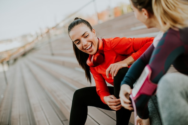 Photo deux jeunes coureur féminin attrayant prenant une pause après avoir fait du jogging à l'extérieur