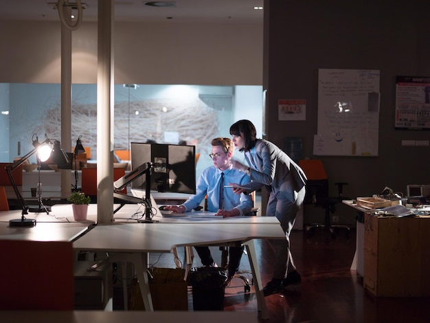 Deux jeunes designers travaillent sur un nouveau projet dans le bureau de nuit en utilisant la technologie moderne