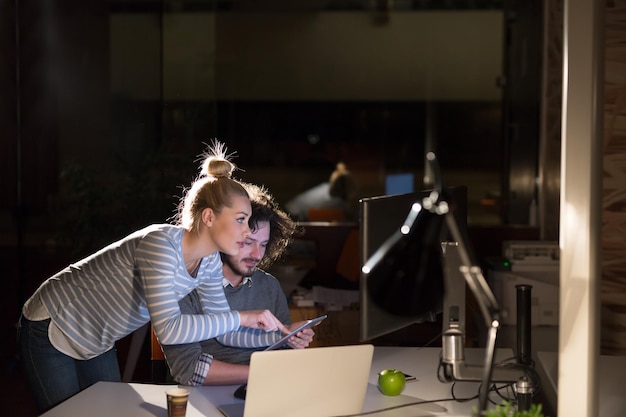 Deux jeunes designers travaillent sur un nouveau projet dans le bureau de nuit en utilisant la technologie moderne