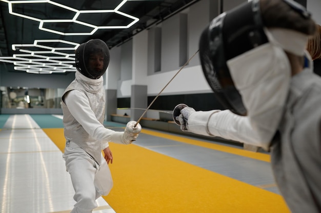 Deux jeunes épéistes en uniforme pratiquant l'attaque et la défense pendant l'entraînement. Ecole d'art martial