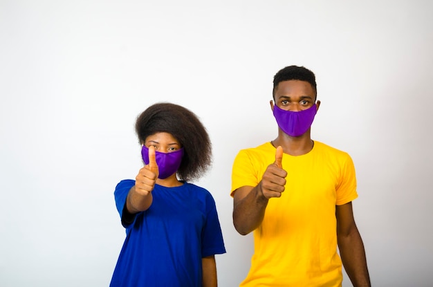 Deux jeunes étudiants africains isolés sur fond blanc portant un masque facial pour se protéger de l'épidémie dans la société