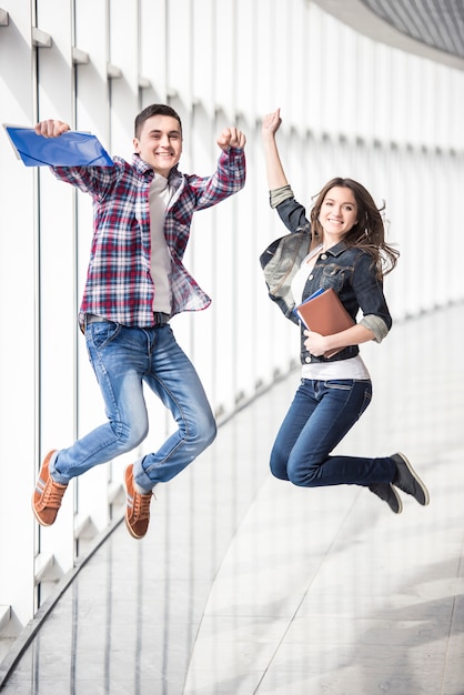 Photo deux jeunes étudiants heureux sautant au collège.