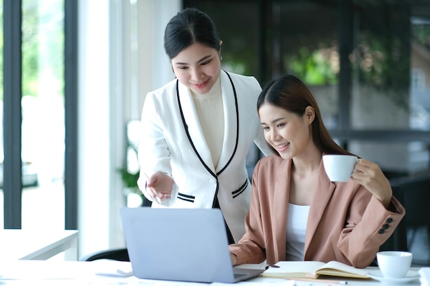 Deux jeunes femmes d'affaires asiatiques discutent avec un nouveau projet de démarrage Présentation d'idées analysent la planification et les statistiques financières et le marché de l'investissement au bureau