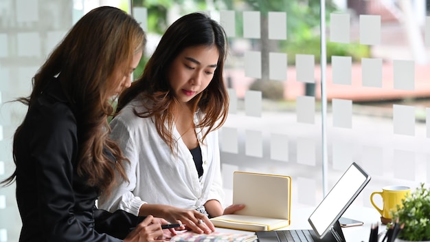 Deux jeunes femmes d'affaires discutant de la planification de la stratégie de leur nouvelle entreprise en démarrage.