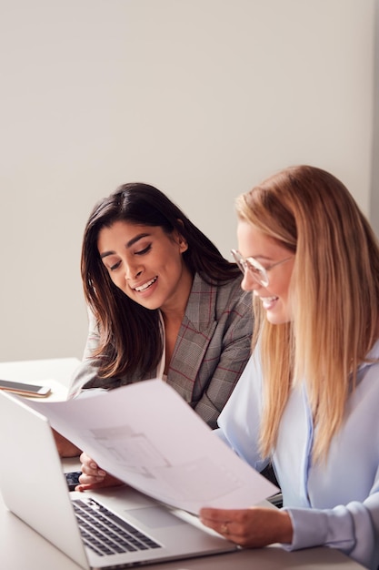 Deux jeunes femmes d'affaires en réunion autour d'une table dans un espace de travail moderne discutant de documents