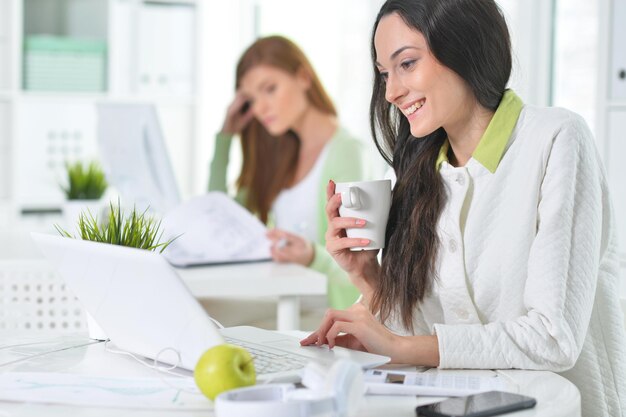 Deux jeunes femmes d'affaires travaillant dans un bureau moderne pendant l'heure du déjeuner