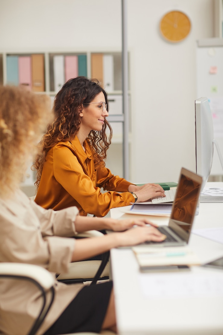 Photo deux jeunes femmes d'affaires travaillant sur des ordinateurs