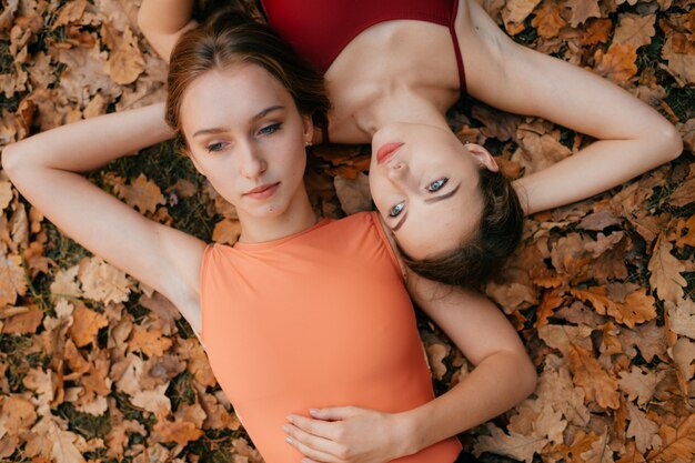 Deux jeunes femmes allongées sur des feuilles d'automne.