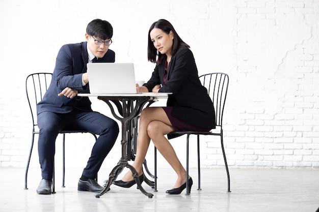 Deux jeunes femmes asiatiques et un homme travaillant avec un ordinateur portable