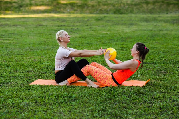 Deux jeunes femmes assises dans le parc et faisant du fitness avec le ballon