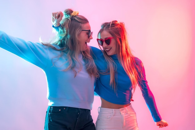 Deux jeunes femmes caucasiennes blondes dansant en discothèque souriant et s'amusant à la fête