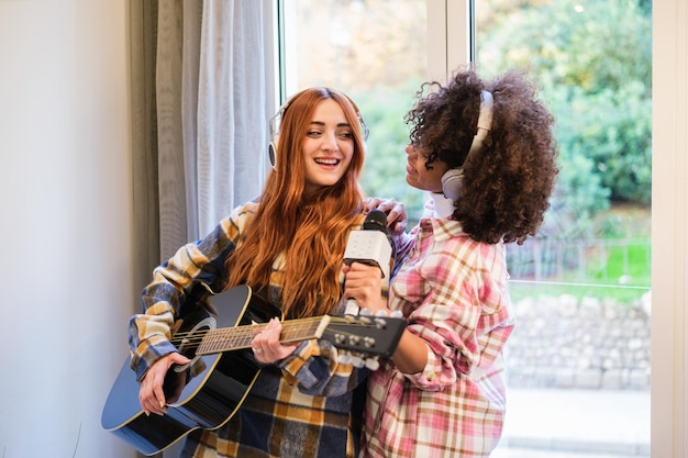 Deux jeunes femmes chantant et jouant de la guitare à la maison et faisant de la musique ensemble Style de vie karaoké musique concept