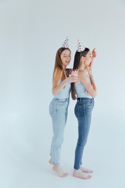 Deux jeunes femmes en chapeaux d'anniversaire célébrant l'anniversaire