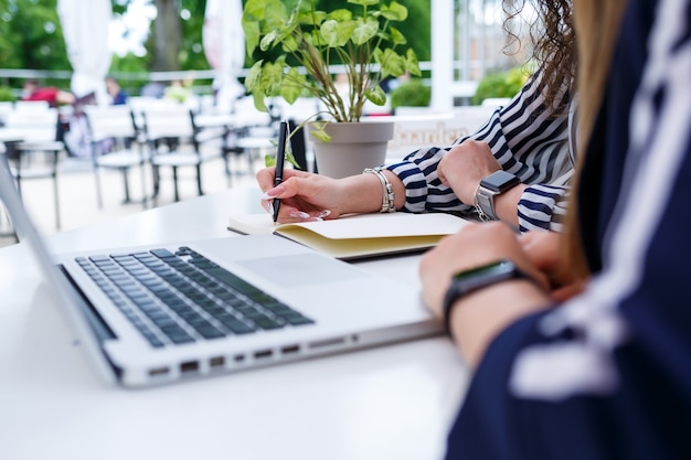 Deux jeunes femmes chefs d'entreprise prospères sont assises à une table avec un ordinateur portable et un ordinateur portable travaillant sur un nouveau projet de développement, des étudiantes rédigent un rapport sur le travail de leur ordinateur