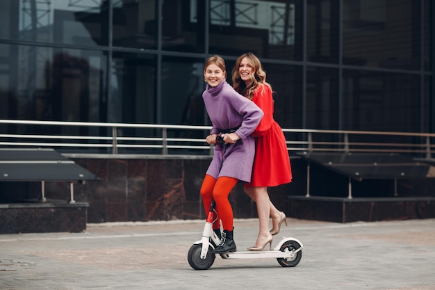 Deux jeunes femmes à cheval sur un scooter électrique à la ville