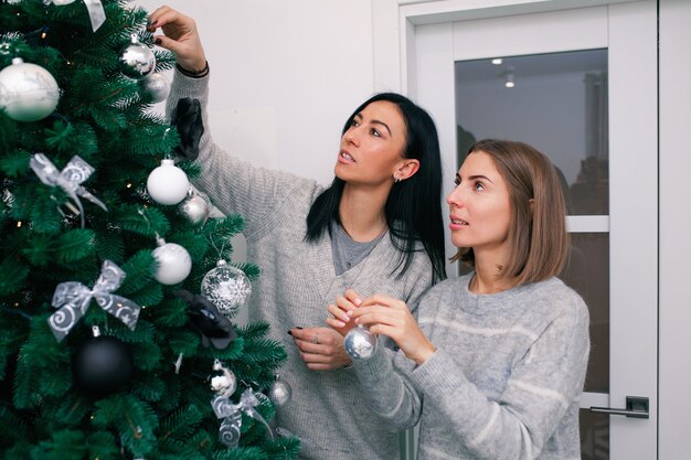 Deux jeunes femmes décorent le sapin de Noël