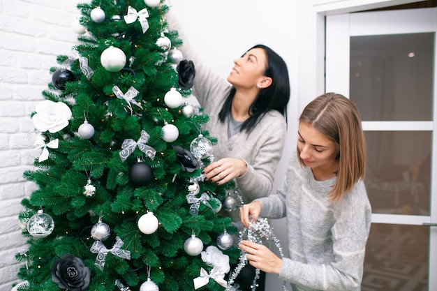 Deux jeunes femmes décorent le sapin de Noël