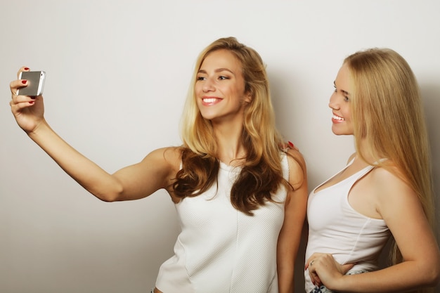 Deux jeunes femmes drôles prenant selfie avec téléphone portable