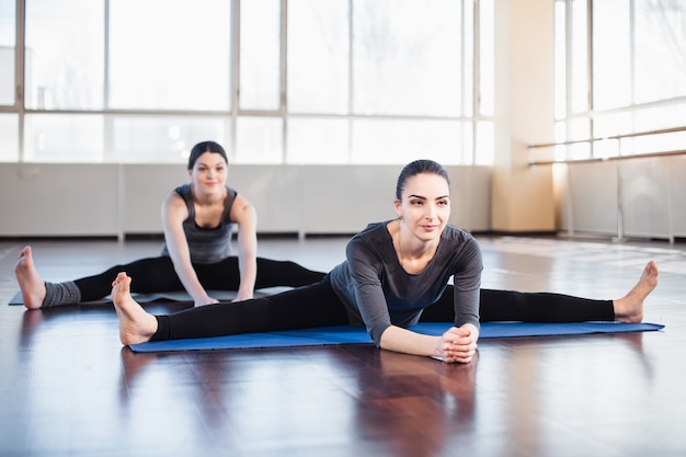 Deux jeunes femmes faisant des étirements dans la salle de fitness