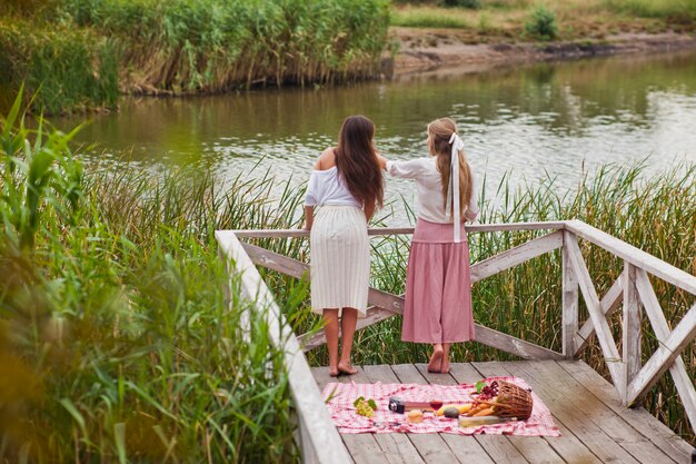 Photo deux jeunes femmes gaies ont un pique-nique en plein air un jour d'été.