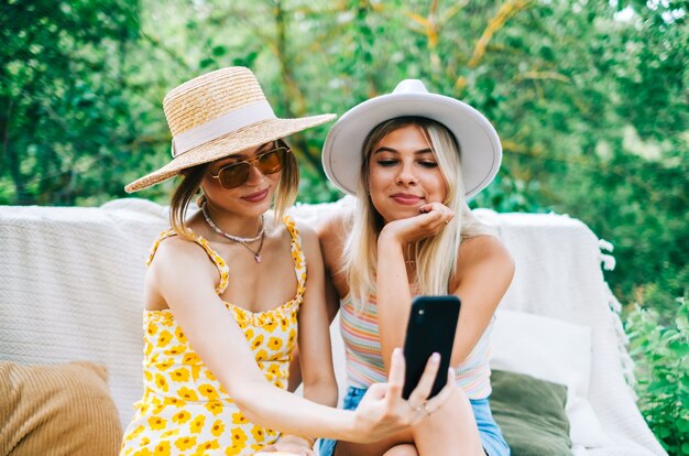 Deux jeunes femmes gaies s'amusant et faisant des photos en plein air dans le jardin.