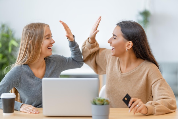 Deux jeunes femmes heureuses faisant des achats en ligne. Filles faisant du shopping à la maison.