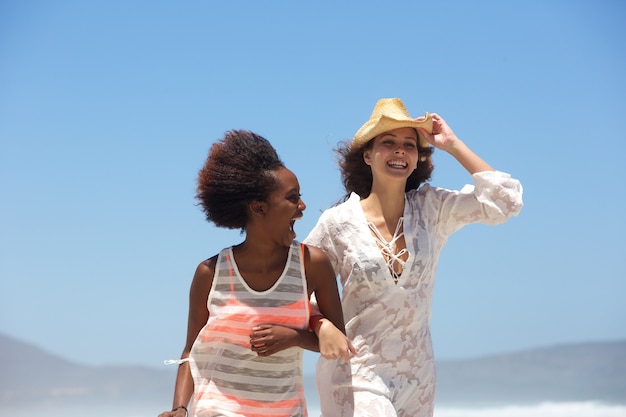 Deux jeunes femmes heureux marchant sur la plage ensemble