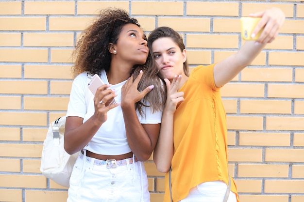 Deux jeunes femmes hipster souriantes en vêtements d'été posant dans la rue. Femme montrant des émotions positives pour le visage.