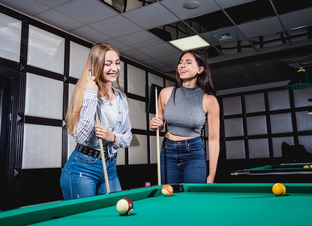 Deux jeunes femmes jouant au billard.