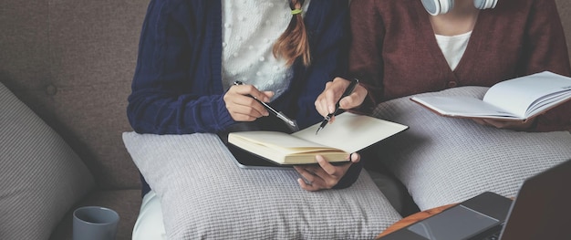 Deux jeunes femmes pensant avec un livre sur un canapé dans le salon à la maison