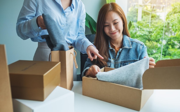 Deux jeunes femmes recevant et ouvrant une boîte postale de vêtements à la maison pour la livraison et le concept d'achat en ligne