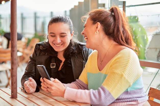 Photo deux jeunes femmes s'amusant par une journée ensoleillée au café en plein air