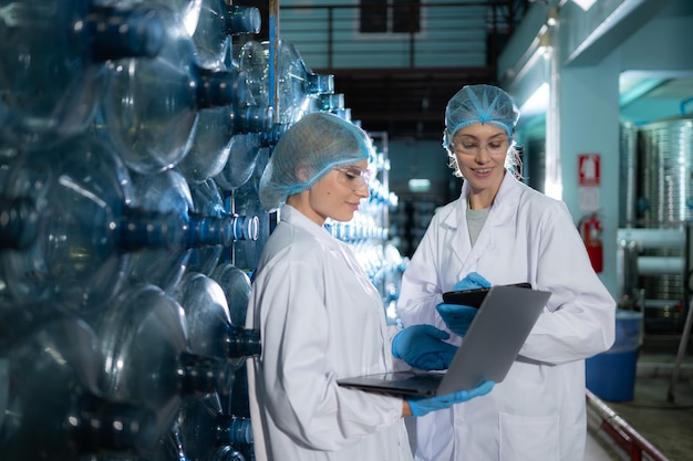 Deux jeunes femmes scientifiques travaillant avec un ordinateur tablette dans une usine d'eau potable